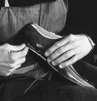 A close-up of hands working on the sole of a leather shoe